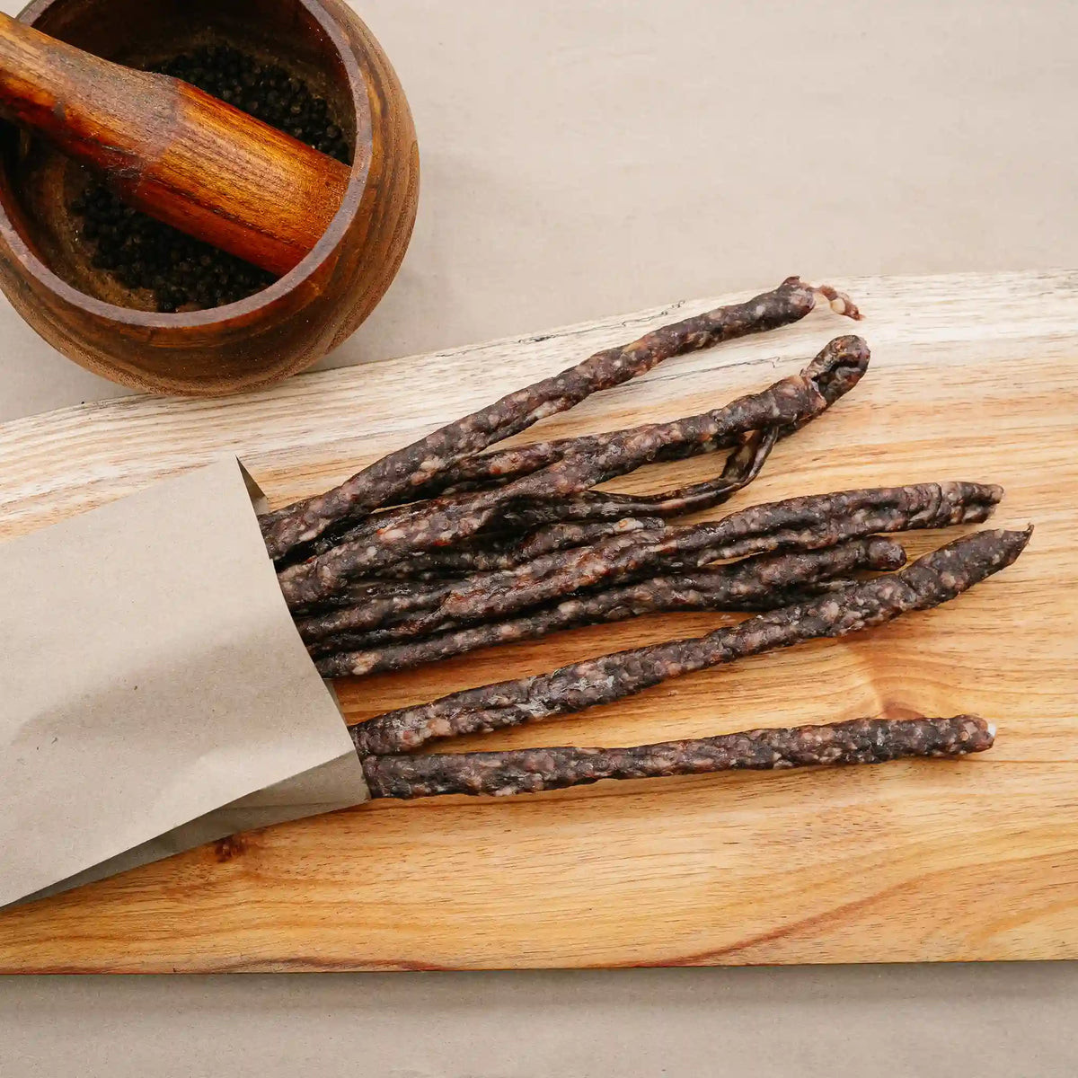 Wagyu droëwors from Greeff's Butchery, Knysna, in a paper sleeve on a wooden board.